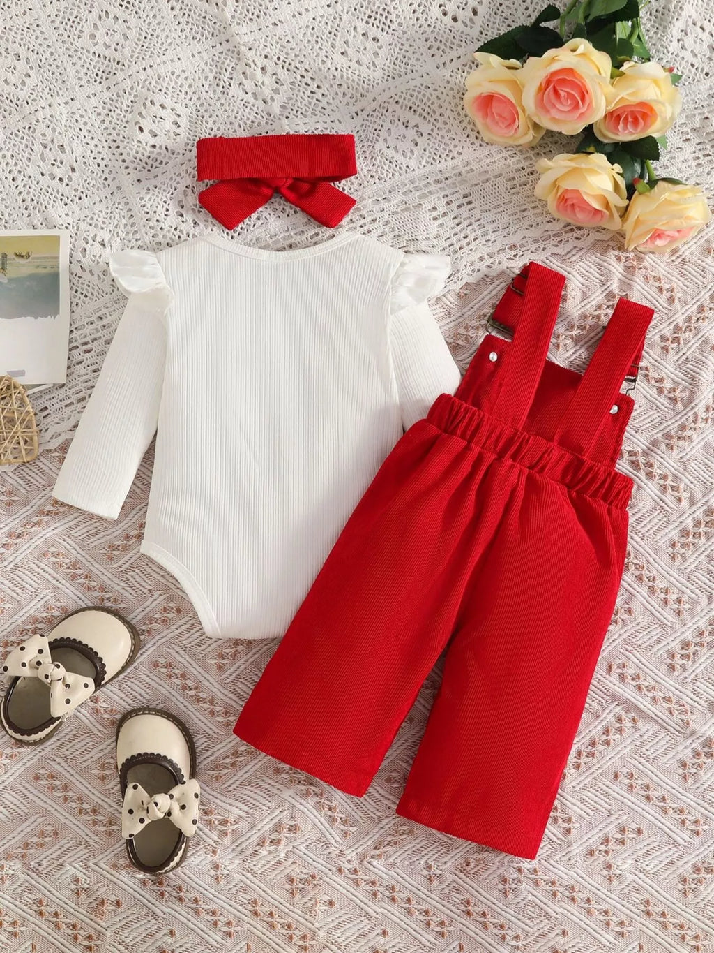 White ribbed baby bodysuit with red bow-embroidered overalls and matching headband displayed flat