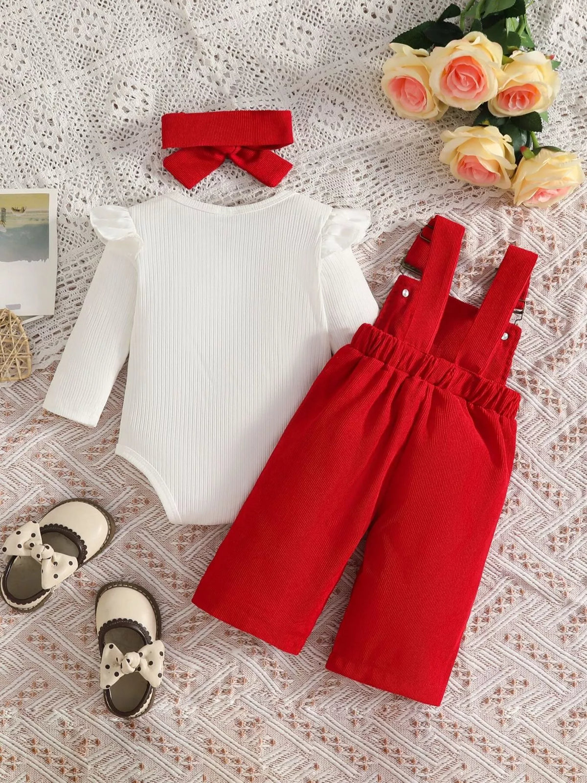 White ribbed baby bodysuit with red bow-embroidered overalls and matching headband displayed flat