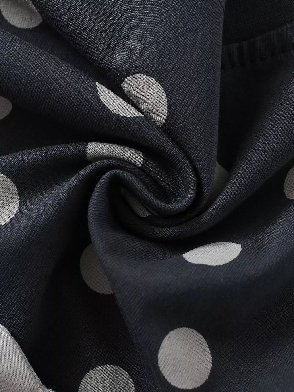 Folded dark fabric showing the light polka-dot print.