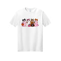 Front view of a white short-sleeve T-shirt showing four ghosts in pink plaid, leopard print, and Halloween patterns, wearing large bows and holding drinks and candy buckets.